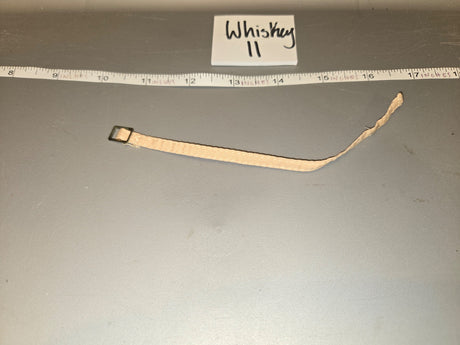 Looking at the item, it appears to be a watch strap/band with a small buckle hardware, measuring approximately 7-8 inches long against the ruler, consistent with 1/6 scale. The tag reads "Whiskey II". 1/6 Scale WWII US Watch Strap - Whiskey II